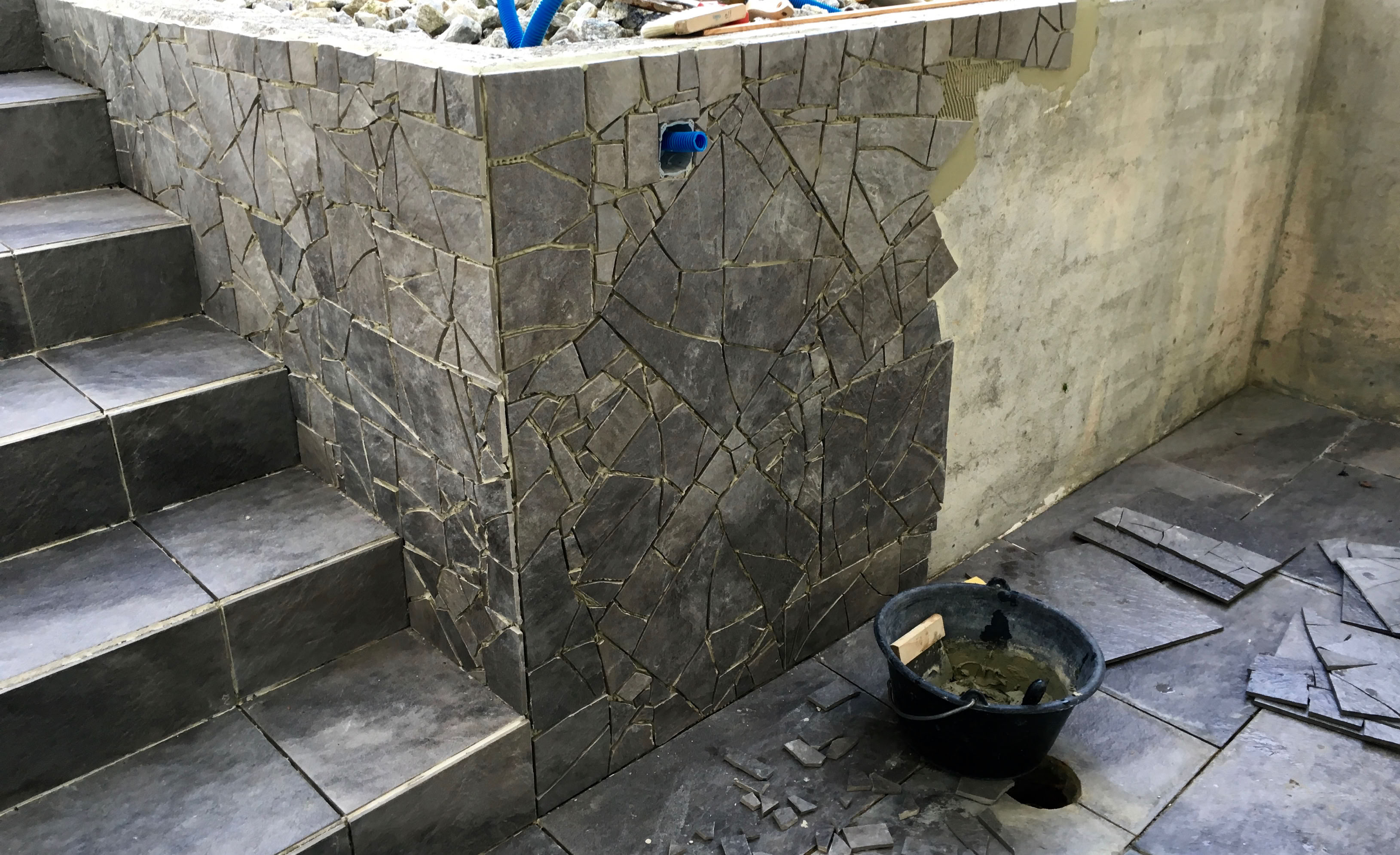 Aufbau des Fliesenmosaiks an einer Betonmauer