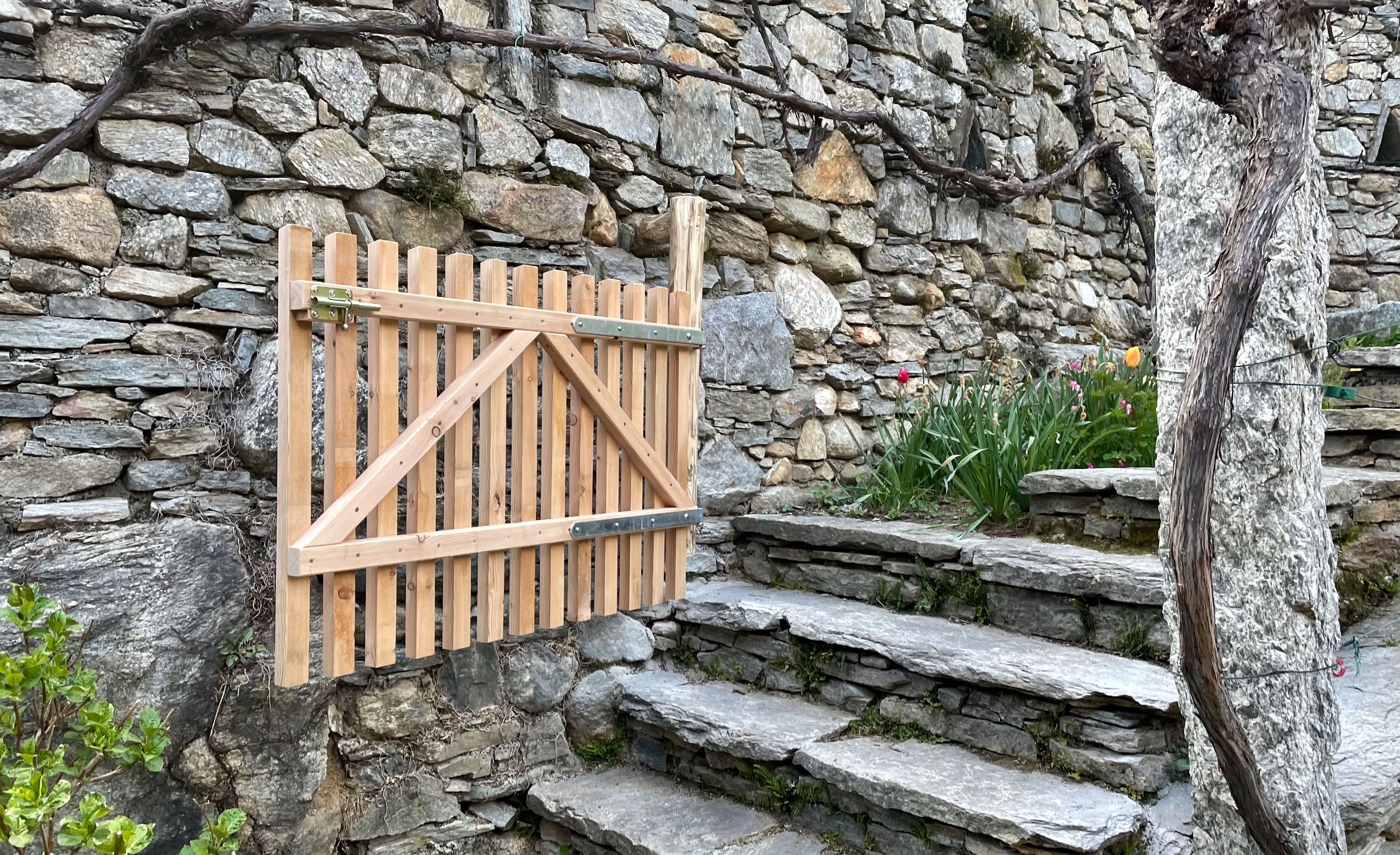 Angefertigtes Gartentor Holz aus Lärche inmitten einer grossen Trockensteinmauer