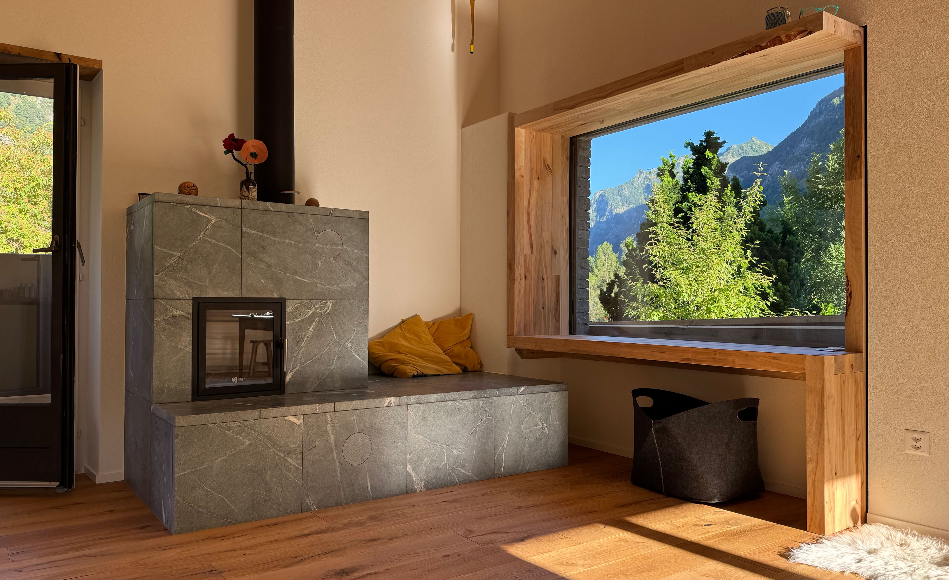Klebend verlegter Eichenparkett auf mineralischen Boden. Anschmiegsam und gemütlich präsentiert sich der graue Bündner Specksteinofen