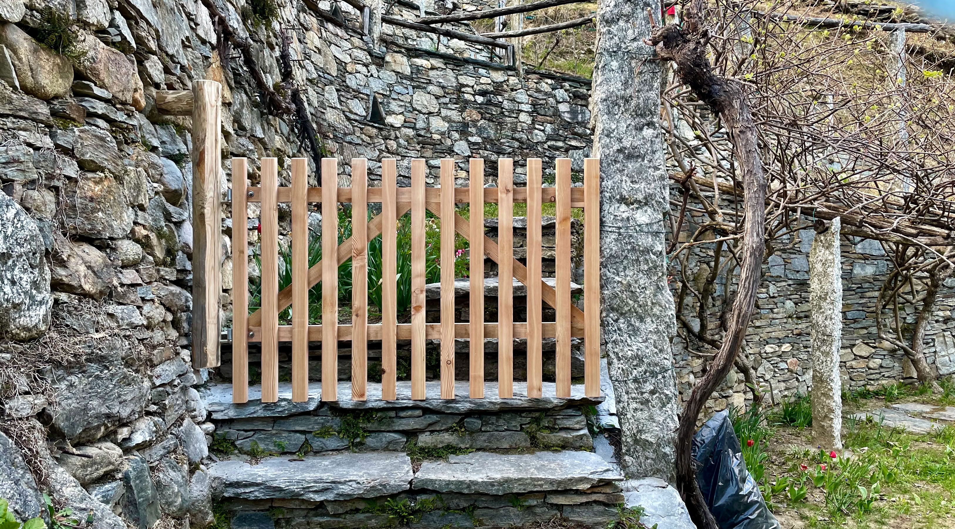 Das fertig montierte Gartentor aus Holz inmitten Weinreben