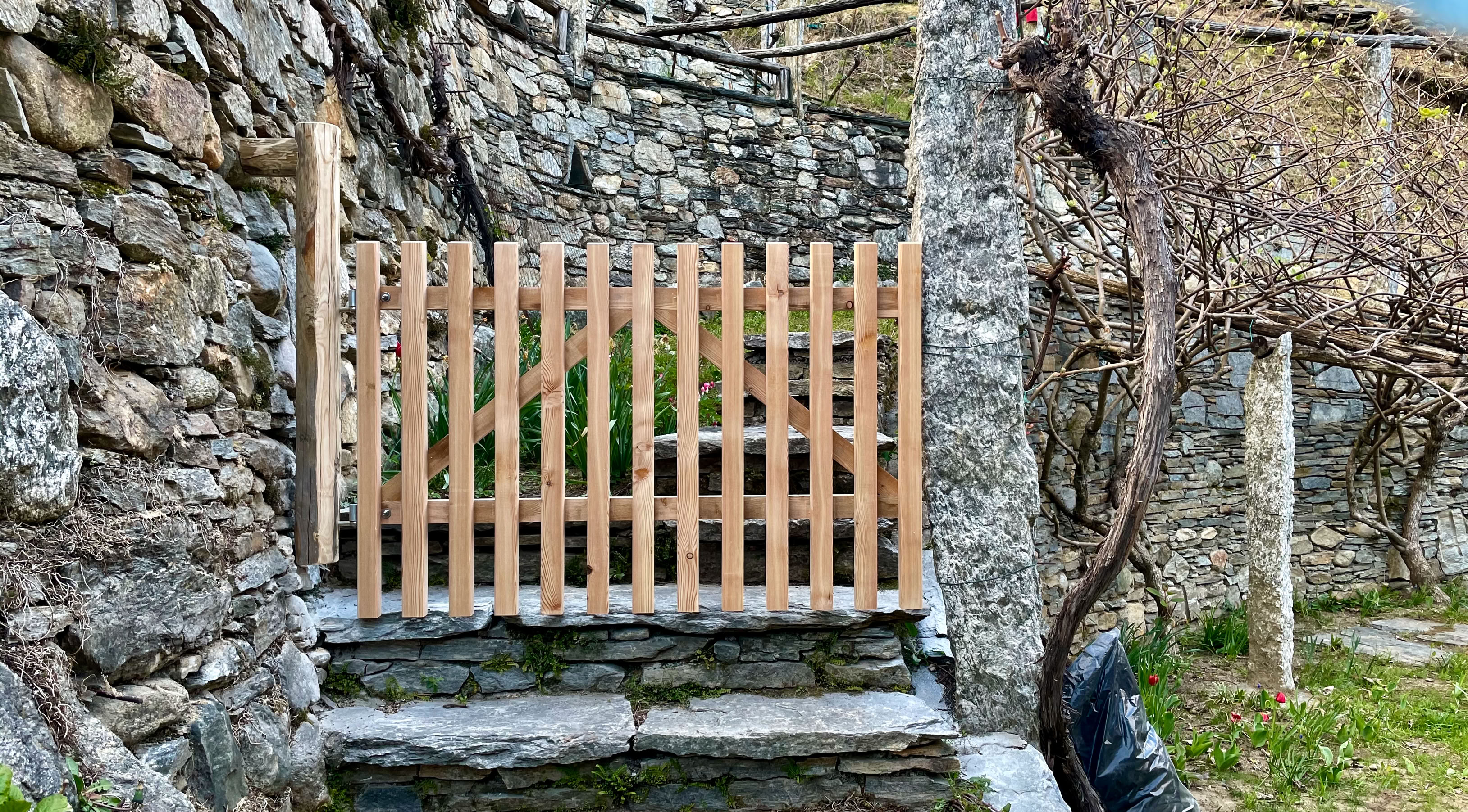 Das fertig montierte Gartentor aus Holz inmitten Weinreben